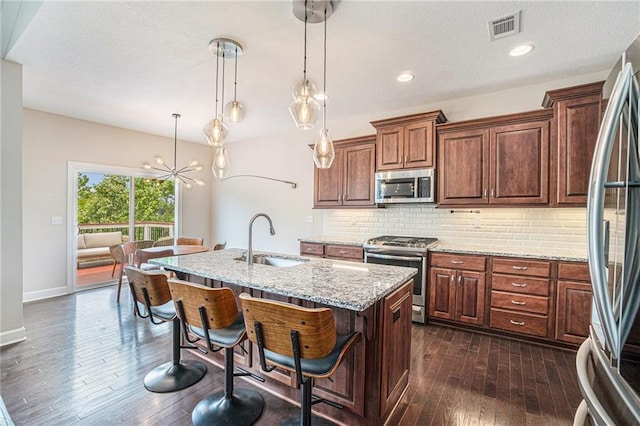 24842 W 144th St, Olathe, KS 66061 - kitchen featuring stainless steel appliances, a sink, dark wood-style flooring, tasteful backsplash, and light stone countertops