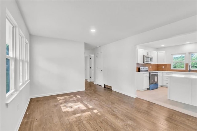 12926 Virginia Ave, Kansas City, MO 64146 - unfurnished living room with baseboards, light wood-type flooring, recessed lighting, and a sink