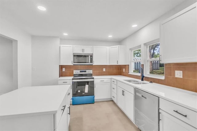 12926 Virginia Ave, Kansas City, MO 64146 - kitchen with stainless steel appliances, a sink, light countertops, white cabinets, and decorative backsplash