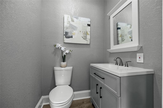 3332 Flora Ave, Kansas City, MO 64109 - half bath with vanity, toilet, wood finished floors, a textured wall, and baseboards