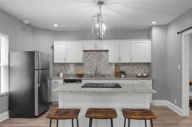 3332 Flora Ave, Kansas City, MO 64109 - kitchen featuring stainless steel appliances, a sink, light wood-style flooring, a kitchen breakfast bar, and recessed lighting
