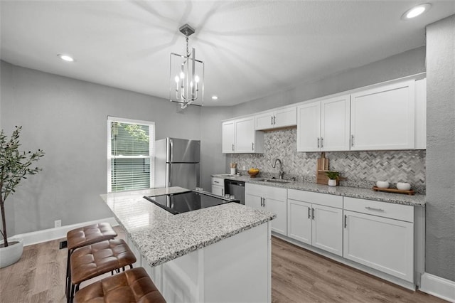 3332 Flora Ave, Kansas City, MO 64109 - kitchen with freestanding refrigerator, tasteful backsplash, a sink, white cabinets, and wood finished floors