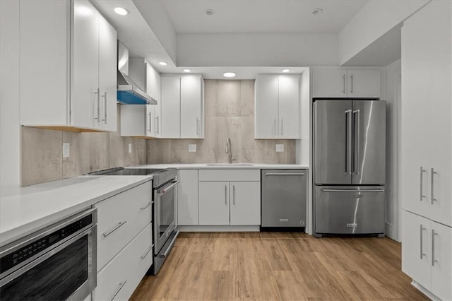 9100 Lamar Ave Unit 107, Overland Park, KS 66207 - kitchen featuring appliances with stainless steel finishes, wall chimney range hood, white cabinetry, light countertops, and recessed lighting