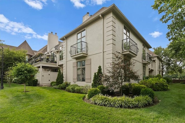 9100 Lamar Ave Unit 107, Overland Park, KS 66207 - view of side of property featuring a balcony, a chimney, a yard, and stucco siding