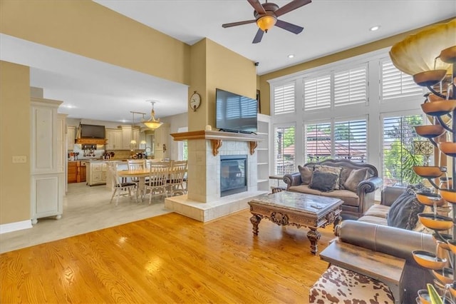 8506 W 155th Pl, Overland Park, KS 66223 - living area featuring light wood-style floors, ceiling fan, a high ceiling, a tiled fireplace, and recessed lighting