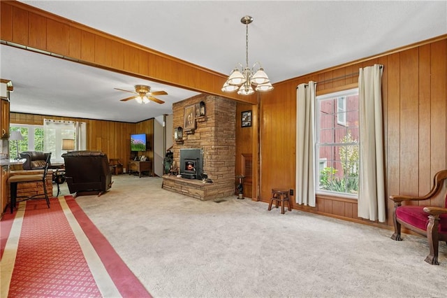 5201 Noland Rd, Kansas City, MO 64133 - carpeted living area featuring wooden walls, a wood stove, a chandelier, and ceiling fan