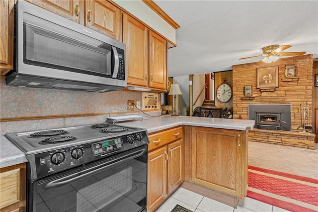 5201 Noland Rd, Kansas City, MO 64133 - kitchen with black electric range, stainless steel microwave, a peninsula, open floor plan, and a large fireplace