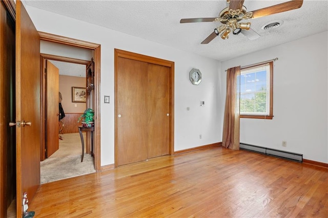 5201 Noland Rd, Kansas City, MO 64133 - unfurnished bedroom with a baseboard radiator, light wood-style floors, a textured ceiling, a closet, and a ceiling fan