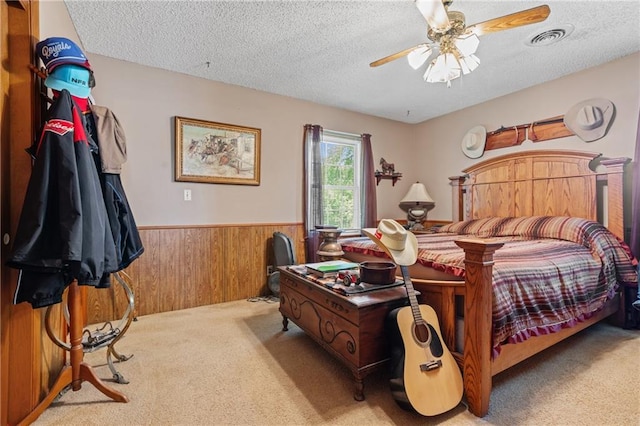 5201 Noland Rd, Kansas City, MO 64133 - carpeted bedroom with wainscoting, a textured ceiling, wood walls, and a ceiling fan