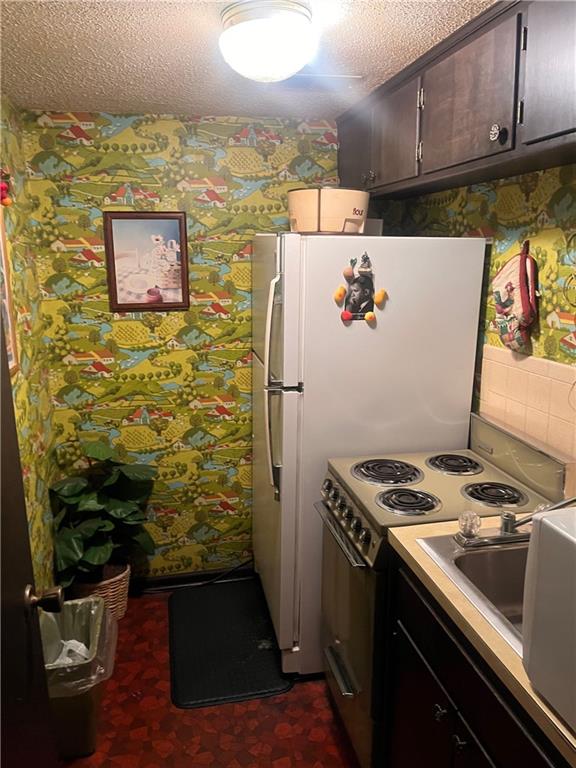 2501 N 73rd Ter, Kansas City, KS 66109 - kitchen featuring range with electric stovetop, a textured ceiling, light countertops, and decorative backsplash