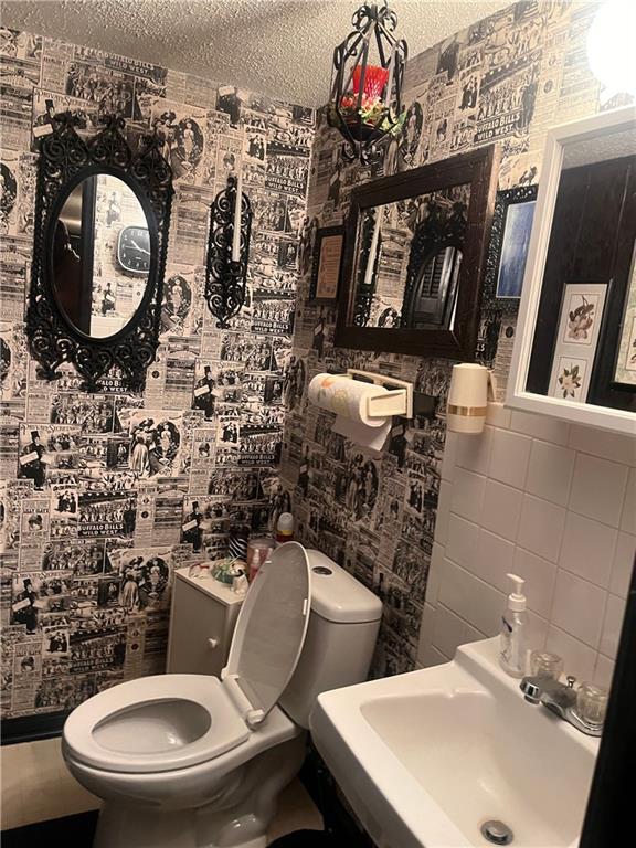 2501 N 73rd Ter, Kansas City, KS 66109 - half bath with tile walls and a textured ceiling