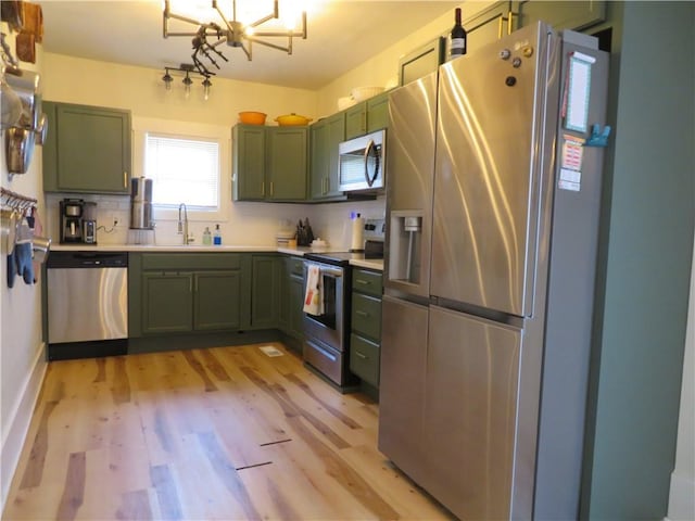 205 W Wea St, Paola, KS 66071 - kitchen with green cabinets, appliances with stainless steel finishes, light wood-style flooring, light countertops, and a chandelier