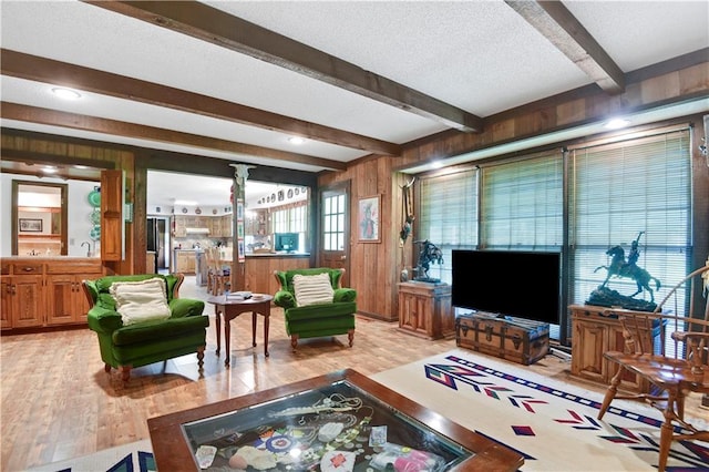 11814 W 149th St, Olathe, KS 66062 - living area with beamed ceiling, light wood-style floors, wooden walls, decorative columns, and a textured ceiling