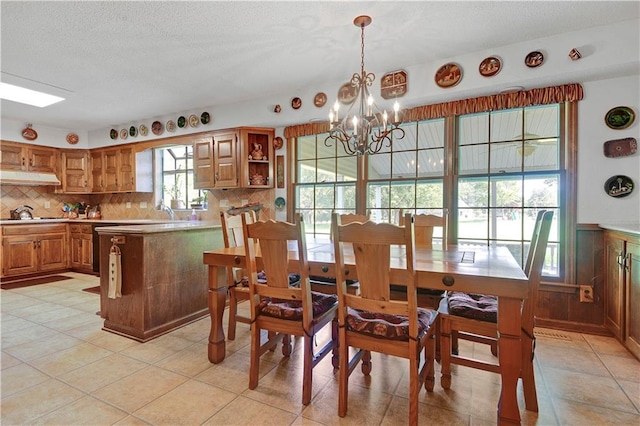 11814 W 149th St, Olathe, KS 66062 - dining area with a chandelier, a textured ceiling, wainscoting, and light tile patterned floors