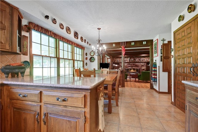11814 W 149th St, Olathe, KS 66062 - kitchen featuring a chandelier, brown cabinets, a textured ceiling, light tile patterned flooring, and backsplash