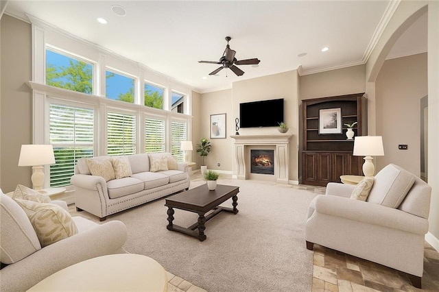 4512 NE Parks Summit Ter, Lees Summit, MO 64064 - living area featuring crown molding, a ceiling fan, a fireplace with flush hearth, recessed lighting, and arched walkways