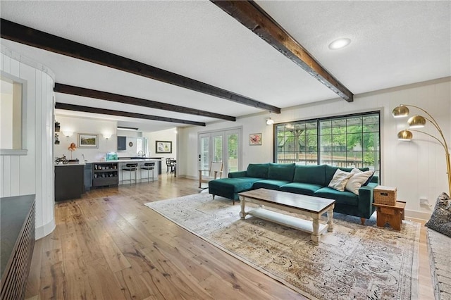 3632 NW Blue Jacket Dr, Lees Summit, MO 64064 - living room featuring light wood finished floors, a textured ceiling, beam ceiling, and baseboards