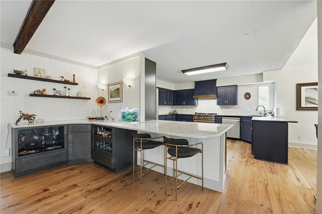 3632 NW Blue Jacket Dr, Lees Summit, MO 64064 - kitchen featuring a peninsula, custom exhaust hood, stainless steel appliances, light wood-style flooring, and a breakfast bar