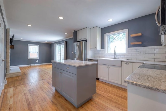5917 W 101st Ter, Overland Park, KS 66207 - kitchen with appliances with stainless steel finishes, a kitchen island, light wood finished floors, tasteful backsplash, and ornamental molding
