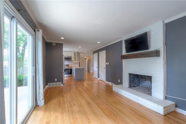 5917 W 101st Ter, Overland Park, KS 66207 - unfurnished living room with a fireplace, crown molding, light wood finished floors, and recessed lighting