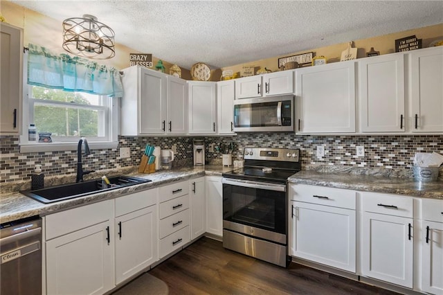 302 W 4th St, Waverly, KS 66871 - kitchen with stainless steel appliances, a sink, a textured ceiling, dark wood-style floors, and decorative backsplash