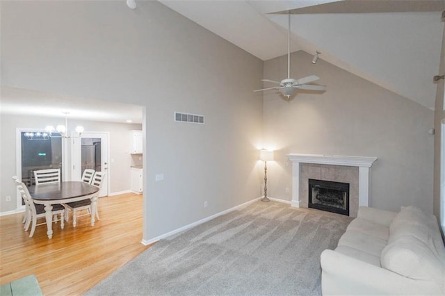 7503 N Lewis Ave, Kansas City, MO 64158 - living area featuring a tile fireplace, high vaulted ceiling, ceiling fan, a chandelier, and wood finished floors