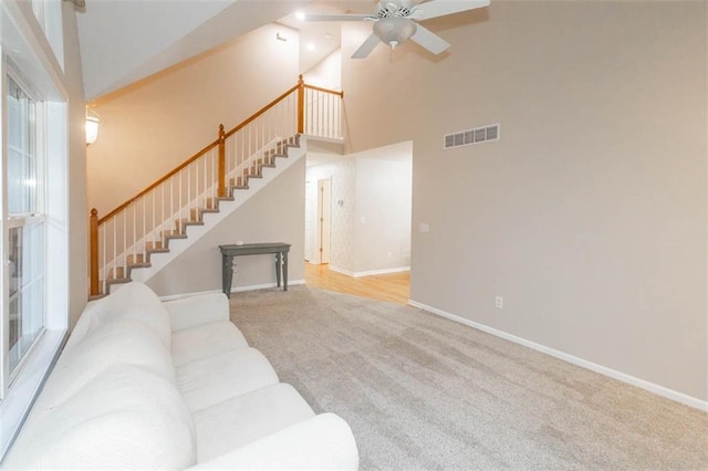 7503 N Lewis Ave, Kansas City, MO 64158 - unfurnished living room featuring stairs, ceiling fan, carpet flooring, and a towering ceiling