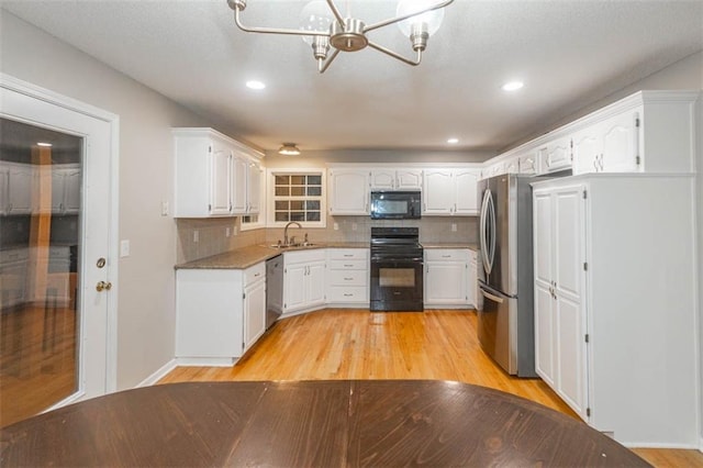 7503 N Lewis Ave, Kansas City, MO 64158 - kitchen featuring black appliances, a chandelier, light wood-type flooring, white cabinets, and backsplash