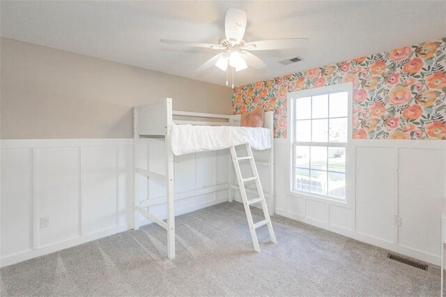 7503 N Lewis Ave, Kansas City, MO 64158 - bedroom featuring a decorative wall, a wainscoted wall, light carpet, a ceiling fan, and wallpapered walls