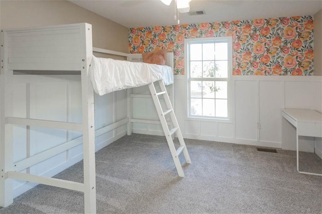 7503 N Lewis Ave, Kansas City, MO 64158 - unfurnished bedroom featuring a decorative wall, multiple windows, wainscoting, carpet floors, and wallpapered walls
