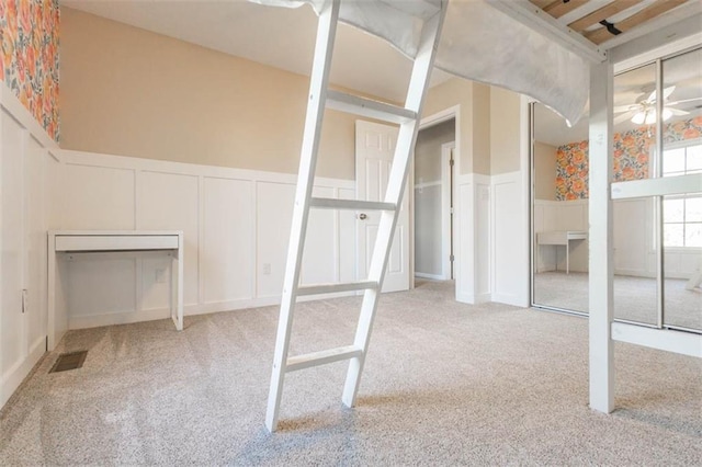 7503 N Lewis Ave, Kansas City, MO 64158 - unfurnished bedroom featuring a decorative wall, carpet, a wainscoted wall, and multiple closets