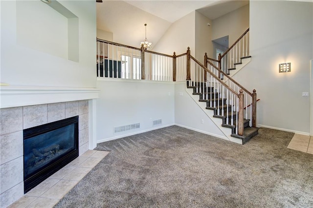 610 SE Joel Ave, Lees Summit, MO 64063 - unfurnished living room with a chandelier, carpet, a tiled fireplace, stairway, and high vaulted ceiling