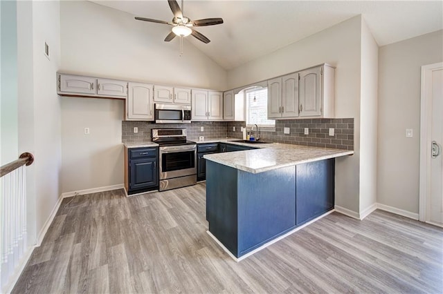 610 SE Joel Ave, Lees Summit, MO 64063 - kitchen featuring appliances with stainless steel finishes, a peninsula, light wood-style floors, ceiling fan, and vaulted ceiling
