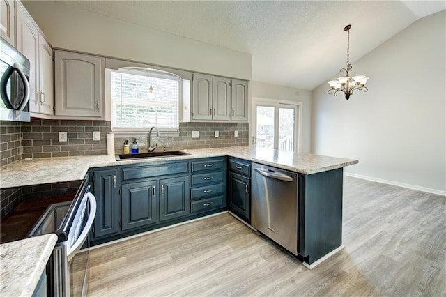 610 SE Joel Ave, Lees Summit, MO 64063 - kitchen with appliances with stainless steel finishes, a peninsula, vaulted ceiling, light wood finished floors, and decorative backsplash