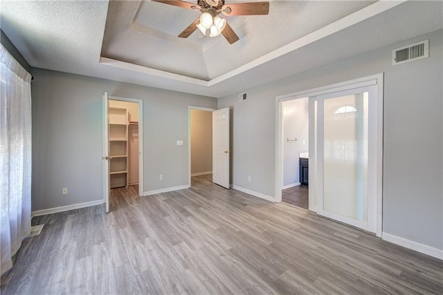 610 SE Joel Ave, Lees Summit, MO 64063 - unfurnished bedroom with wood finished floors, a spacious closet, a raised ceiling, a closet, and ensuite bathroom