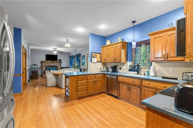 4022 SW Flintrock Dr, Lees Summit, MO 64082 - kitchen featuring a sink, stainless steel appliances, a peninsula, brown cabinets, and light wood-type flooring