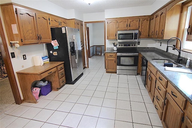 515 Mulberry St, Lees Summit, MO 64086 - kitchen with stainless steel appliances, a sink, brown cabinets, a textured ceiling, and light tile patterned floors