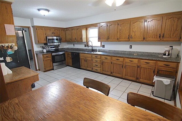 515 Mulberry St, Lees Summit, MO 64086 - kitchen with stainless steel appliances, a sink, brown cabinets, and light tile patterned flooring