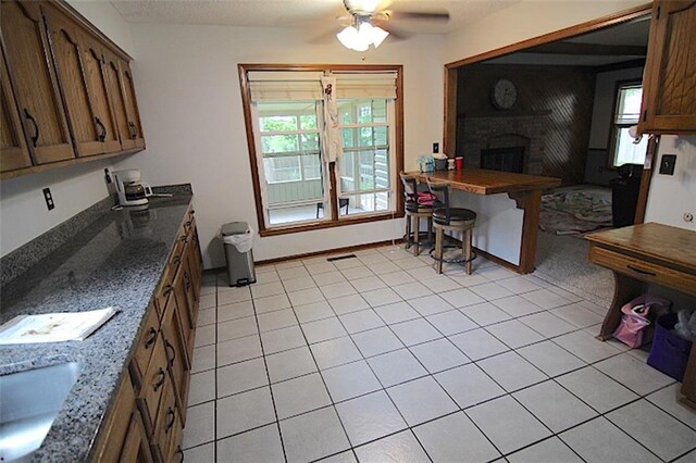 515 Mulberry St, Lees Summit, MO 64086 - kitchen with ceiling fan, a brick fireplace, healthy amount of natural light, and light tile patterned floors