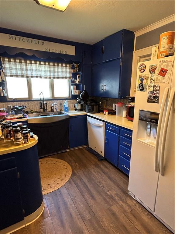112 W Neosho St, Iola, KS 66749 - kitchen with white refrigerator with ice dispenser, blue cabinetry, stainless steel dishwasher, light countertops, and decorative backsplash