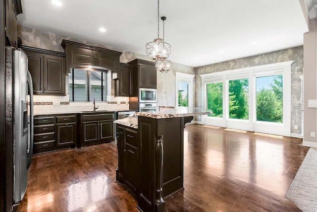 24793 W 98th St, Lenexa, KS 66227 - kitchen with appliances with stainless steel finishes, a center island, dark wood-style flooring, hanging light fixtures, and a kitchen bar