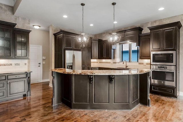 24793 W 98th St, Lenexa, KS 66227 - kitchen featuring stainless steel oven, refrigerator with ice dispenser, built in microwave, decorative backsplash, and light stone counters