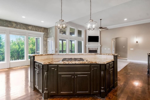 24793 W 98th St, Lenexa, KS 66227 - kitchen with stainless steel gas cooktop, arched walkways, a chandelier, dark wood-type flooring, and a fireplace
