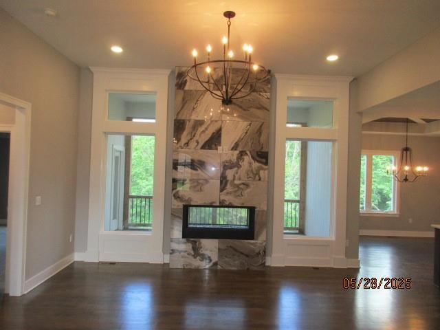 7031 N London Ave, Kansas City, MO 64151 - unfurnished living room with a chandelier, wood finished floors, a multi sided fireplace, baseboards, and recessed lighting