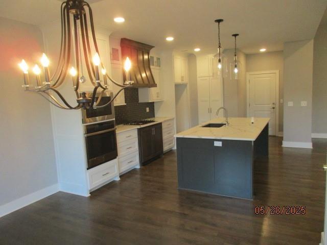 7031 N London Ave, Kansas City, MO 64151 - kitchen featuring a sink, dark wood-style flooring, baseboards, backsplash, and cooktop