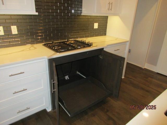 7031 N London Ave, Kansas City, MO 64151 - kitchen with stainless steel gas stovetop, dark wood finished floors, white cabinets, tasteful backsplash, and light stone countertops
