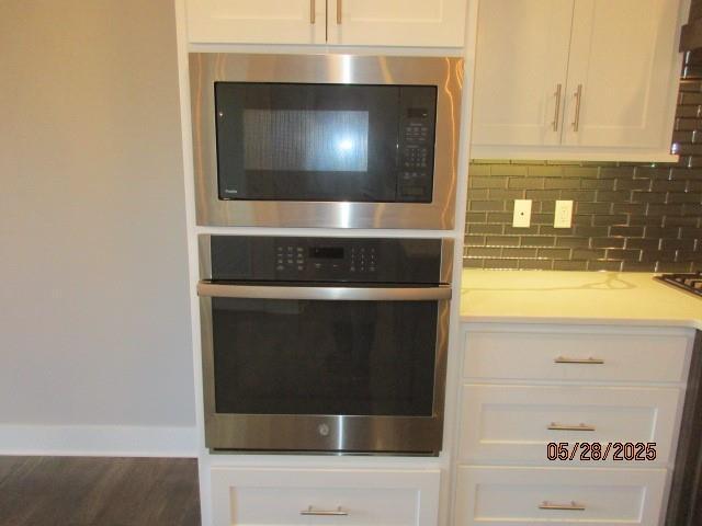7031 N London Ave, Kansas City, MO 64151 - kitchen with appliances with stainless steel finishes, white cabinetry, tasteful backsplash, light countertops, and baseboards