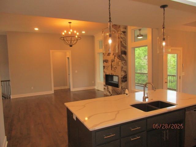 7031 N London Ave, Kansas City, MO 64151 - kitchen featuring a sink, open floor plan, dark wood-style flooring, light stone countertops, and decorative light fixtures