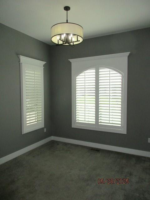 7031 N London Ave, Kansas City, MO 64151 - spare room with a chandelier, dark carpet, and baseboards