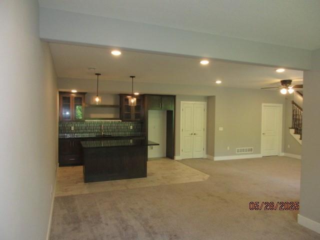 7031 N London Ave, Kansas City, MO 64151 - kitchen with light carpet, dark countertops, decorative backsplash, recessed lighting, and glass insert cabinets
